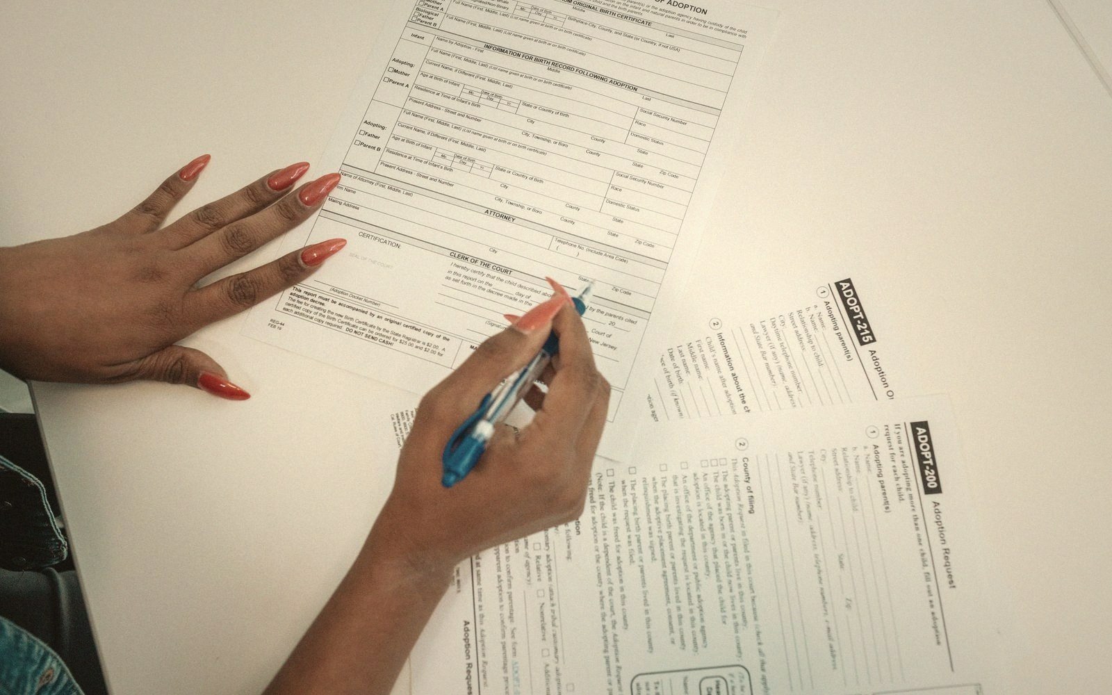 Hands filling out adoption paperwork with a pen on a desk
